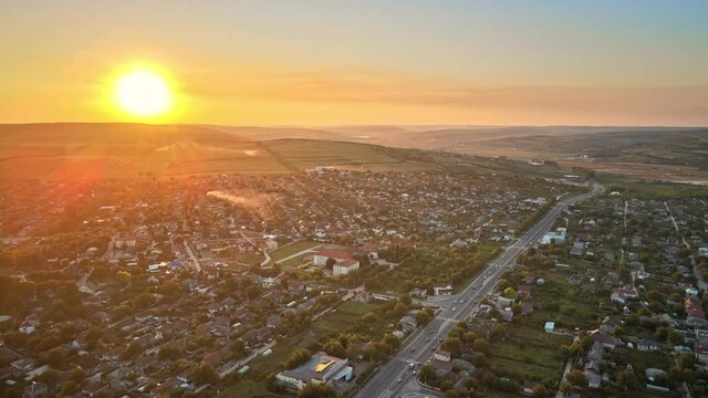 Aerial drone view of Tipova, Moldova at sunset. Road with cars, residential buildings, greenery