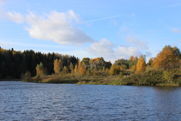 Autumn landscape with lake in the middle of a field and forest.