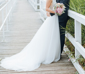 Bride in wedding dress and large train stands next to the groom. Classical wedding 