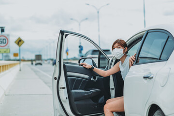 Asian woman   wearing protective face mask protection safety before getting out of the car during coronavirus covid-19 outdoor curfew pandemic