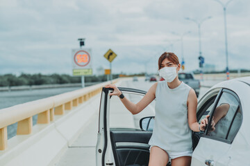 Asian woman   wearing protective face mask protection safety before getting out of the car during coronavirus covid-19 outdoor curfew pandemic