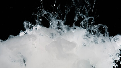White watercolor ink in water on a black background. Meditative magic abstract background. White...