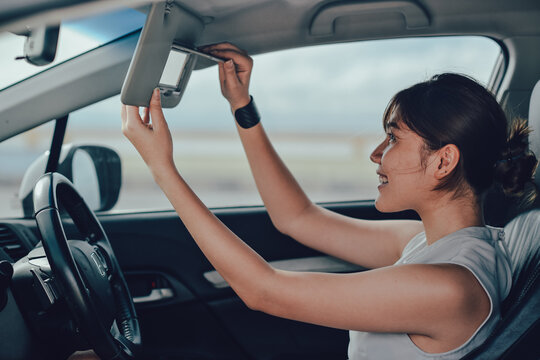 Relaxed asisn woman smiling and looking in mirror. siting on the car. lifestyle and people concept.