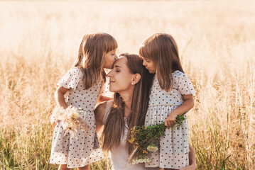 Mom with two twin girls playing in nature in the summer - obrazy, fototapety, plakaty