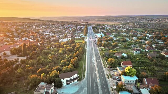 Aerial drone view of Tipova, Moldova at sunset. Road with cars, residential buildings, greenery