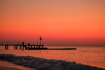 Beautiful sunset sunrise beach with pink sky and pier. Travel, relax and meditation concept. Mediterranian sea