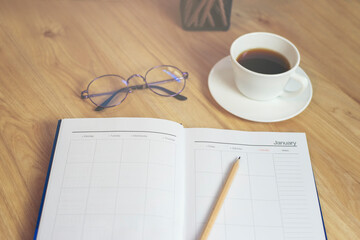 Agenda, planner book, calendar, pencil, and cup of coffee place on office desk. Diary for organizer to plan timetable, daily appointment, and management job at room. Planner book Concept.