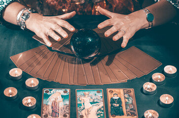Tarot reader with tarot cards.Tarot cards face down on table near burning candles and crystal ball. - obrazy, fototapety, plakaty