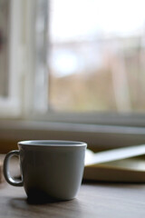 Bowl of cookies, cup of hot beverage, open book and lit candles on a table. Selective focus.