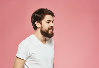 emotional man in a white t-shirt hand gestures anger pink background