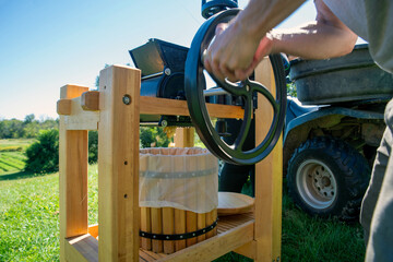 A man turns the flywheel of the apple grinder on a cider press with ATV