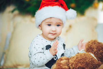 Portrait of beautiful little baby boy celebrates Christmas. New Year's holidays. Adorable funny child in Santa red hat with Christmas gift. Christmas concept