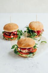 close-up of three burgers on a white table
