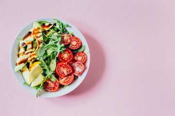 top view of tomato salad arugula avocado lemon in white plate on pink background