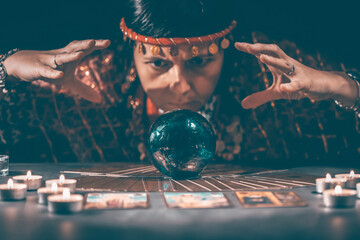 Tarot reader with tarot cards.Tarot cards face down on table near burning candles and crystal ball.