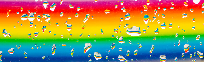 Fototapeta na wymiar A rainbow behind a glass windows with water drops, Point of view, from behind the glass with drops.