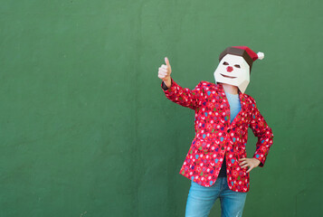 Fototapeta na wymiar Anonymous person dressed in a christmas clothes and mask gesturing to be fine with the finger up