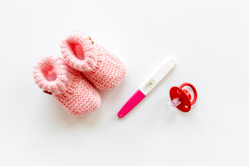 Pregnancy test and pink baby girl booties. Morherhood and pregnancy concept