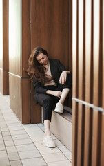 Young millennial businesswoman sitting by the office building