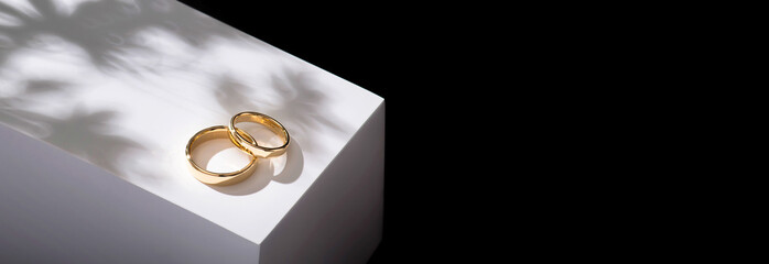 Wedding rings on a wooden box with shadows of leaves