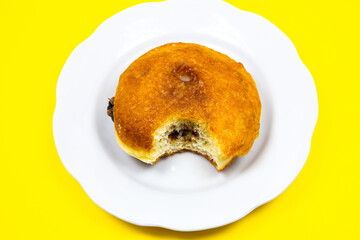 Bitten Donut with chocolate on plate. Delicious sweets temptation and desserts on a yellow background. Minimalism, original and creative image. Beautiful food wallpaper.