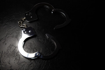 Police metal real handcuffs on the black background. Crime and robbery, prison concept.