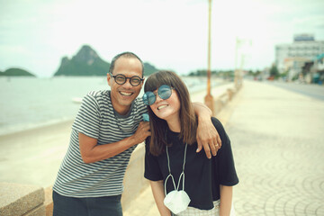 couples of middle age asian laughing with happiness ,standing beside beach