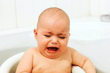Crying baby taking a bath. Baby does not want bathing