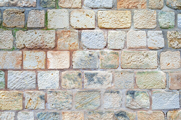 Historic facade of light stone. Wall background with different colored natural stones.