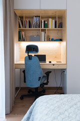 Small office desk with laptop in bedroom of modern apartment