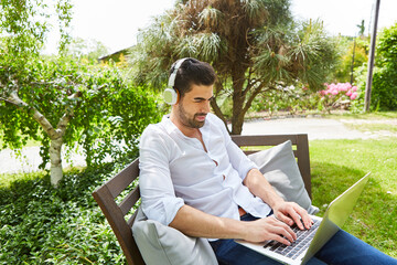 Freelancer man on laptop pc in the garden in summer