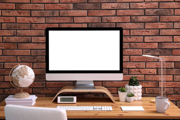 Stylish workplace with modern computer near brick wall indoors. Space for text