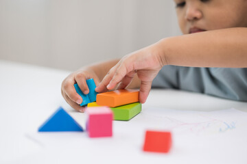 Close up Children hand Practice the skills of playing with wooden toys on the table in living room. Asian little boy education from home. Developing children's learning before entering kindergarten