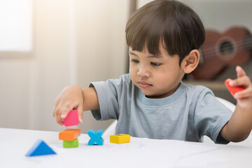 Asian little boy education from home. Developing children's learning before entering kindergarten Practice the skills of playing with wooden toys in living room.