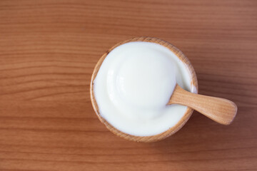 Yogurt in a wooden cup and wooden spoon