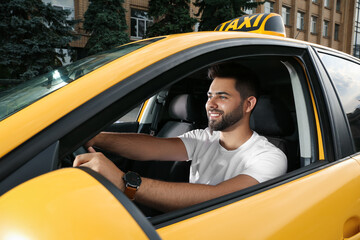 Handsome taxi driver in car on city street - obrazy, fototapety, plakaty