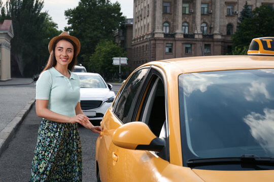 Beautiful Young Woman Getting In Taxi On City Street