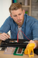 man testing broken laptop with a multimeter