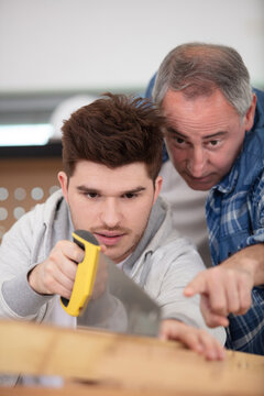 supervisor watching apprentice use handsaw