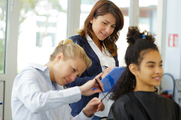 supervisor assessing trainee hairdresser cutting hair