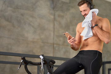 Handsome young man using cellphone during home workout - Powered by Adobe