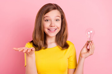 Photo of funny blond teenager girl hold light empty space wear yellow t-shirt isolated on pink color background