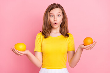 Photo of impressed brown hair teenager girl hold oranges wear yellow t-shirt isolated on pink color background