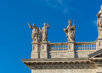 Fototapeta na wymiar Statues on the roof of the Papal Archbasilica of St. John in Lateran (Basilica di San Giovanni in Laterano) in a sunny day, Italy, Rome