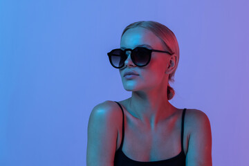 Fashion. Woman in Colorful neon light. Fashionable model portrait in sunglasses creative art neon pink blue light, banner