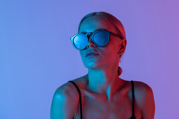 Fashion. Woman in Colorful neon light. Fashionable model portrait in sunglasses creative art neon pink blue light, banner