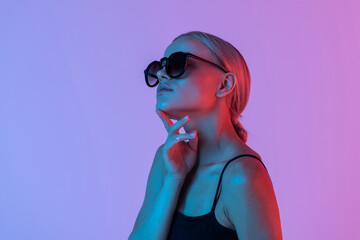 Fashion. Woman in Colorful neon light. Fashionable model portrait in sunglasses creative art neon pink blue light, banner