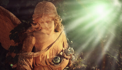 Guardian angel with wings in the sunlight. Antique statue.