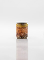 CANNED PICKLED MEAT IN A GLASS JAR, ISOLATED ON A WHITE BACKGROUND