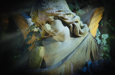 Beauutiful sad angel in the sunlight. Ancient statue. Fragment. Horizontal image.